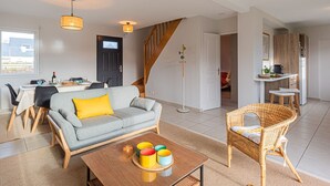Ein modernes Wohnzimmer mit einer Couch, einem Couchtisch und einem Essbereich mit Stühlen und einem Tisch.