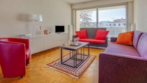 Un salon moderne avec un canapé, un fauteuil rouge et une table basse.