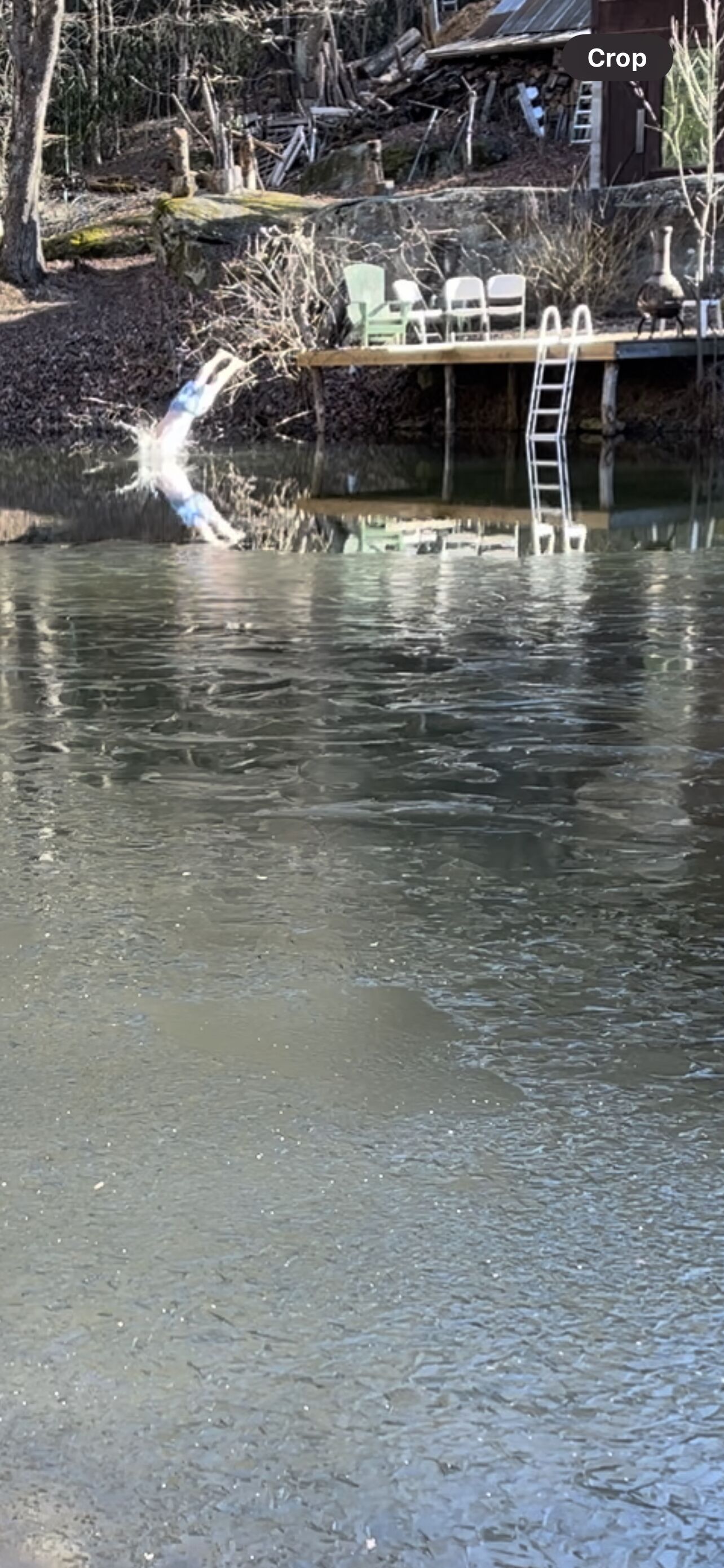 A flooded area with a ladder and chairs near a building.