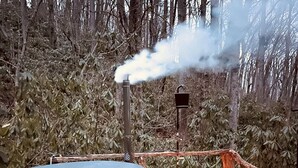 A hot tub surrounded by a wooden deck, with a smoke stack emitting smoke.