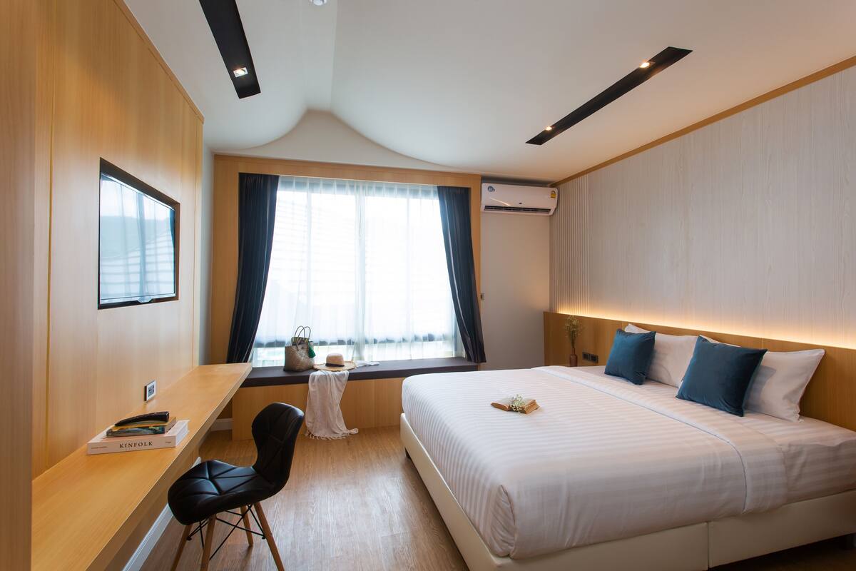 Una camera d'albergo moderna con un ampio letto, una scrivania e una finestra con tende.
