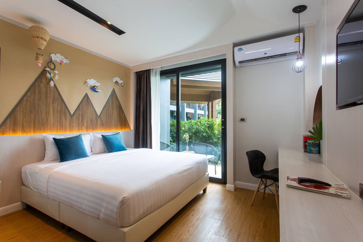 Una camera d'albergo con un letto, una scrivania, una sedia e un'ampia finestra.