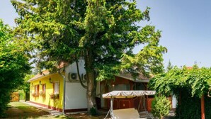 Ein gelbes Haus mit Terrasse, Schaukel und Garten.