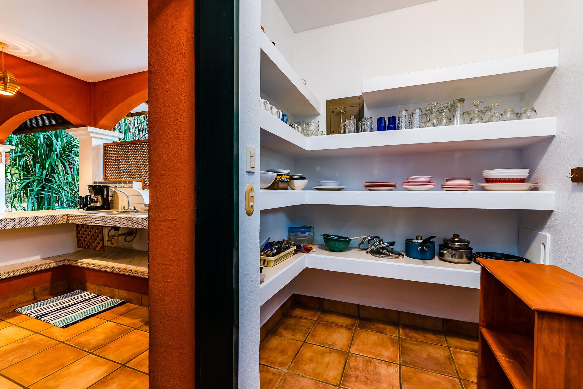 A kitchen with white shelves holding dishes, pots, and utensils.