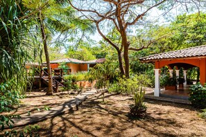 Stroll through the tranquil garden, surrounded by lush greenery and traditional structures with tiled roofs.