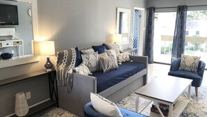 Un salon moderne avec un canapé, des fauteuils, une table basse et un téléviseur.