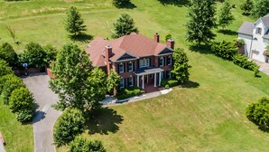 An aerial view of a two-story brick house with a red roof, a front porch, and a well-maintained lawn. - Ridge Creek Getaway, ideal 4 Friends&Family get-togethers, events & receptions.  (Brentwood)