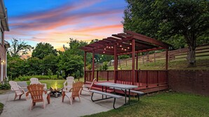 An outdoor patio with Adirondack chairs, a fire pit, and a pergola with string lights. - Ridge Creek Getaway, ideal 4 Friends&Family get-togethers, events & receptions.  (Brentwood)