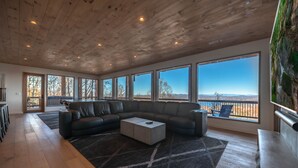 A spacious living area with a large sectional sofa, a coffee table, and a view of the landscape through large windows. - Capstone - Aska Adventure Area (Blue Ridge)
