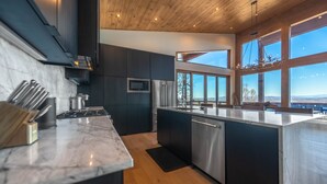 A modern kitchen with dark cabinetry, stainless steel appliances, and a large island. - Capstone - Aska Adventure Area (Blue Ridge)