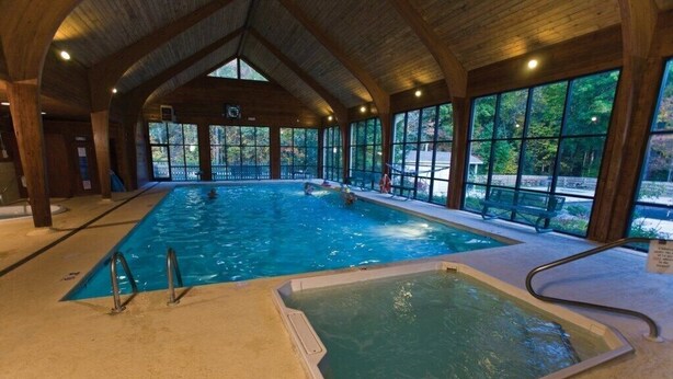 Une piscine intérieure dotée d’un plafond en bois et de grandes fenêtres.