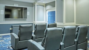 A conference room with gray leather chairs, a large flat-screen TV, and a blue door. - Alexandria | Couples Capital Stay | Gym + WiFi (Alexandria)