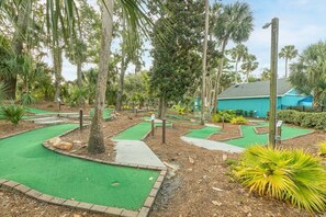 Play a round of mini-golf amidst lush greenery and palm trees.