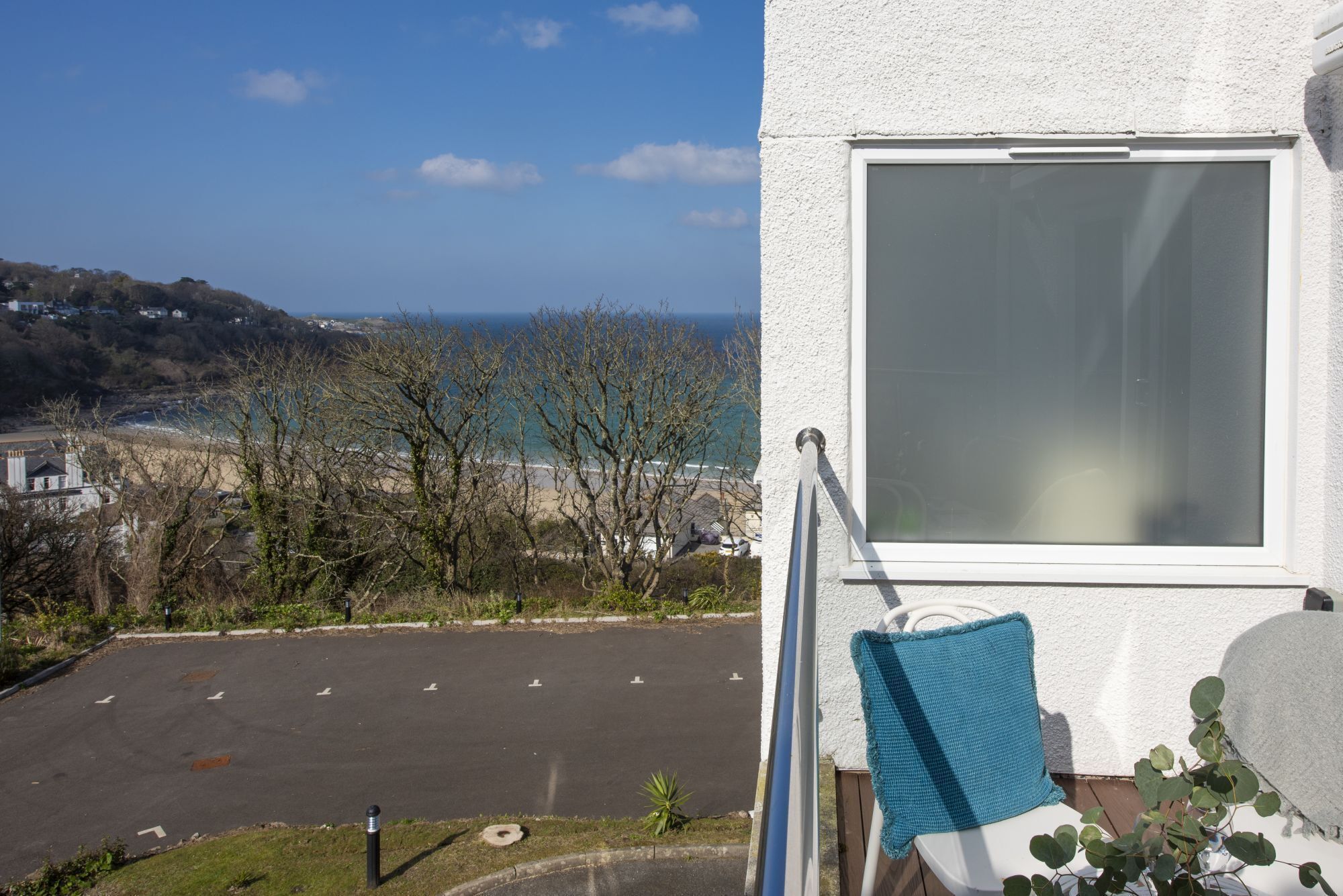 Ein Balkon mit Blick auf einen Parkplatz und das Meer.
