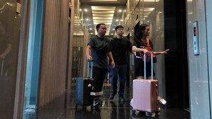 A modern hotel corridor with a reflective floor, a glass elevator, and a person with luggage. - KL Sky Suites KLCC by SA (Kuala Lumpur)