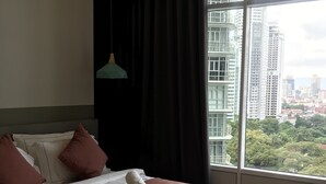 A hotel room with a large bed, a view of the city through a window, and a hanging light fixture. - KL Sky Suites KLCC by SA (Kuala Lumpur)