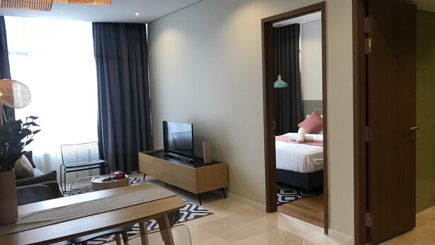 A hotel room with a dining area, a TV on a wooden cabinet, a bed with a pink pillow, and a large mirror. - KL Sky Suites KLCC by SA (Kuala Lumpur)