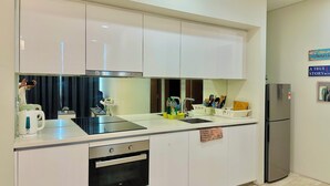 A modern kitchen with white cabinets, a stainless steel refrigerator, and a built-in oven. - KL Sky Suites KLCC by SA (Kuala Lumpur)
