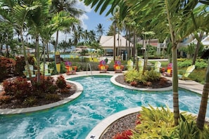 A pool area with multiple water features, surrounded by palm trees and lounge chairs.