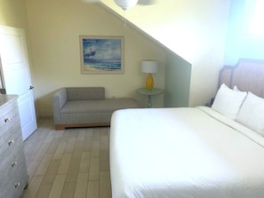 Ein Schlafzimmer mit einem Bett, einem Schlafsofa, einer Lampe, einem Bild und einer Kommode.