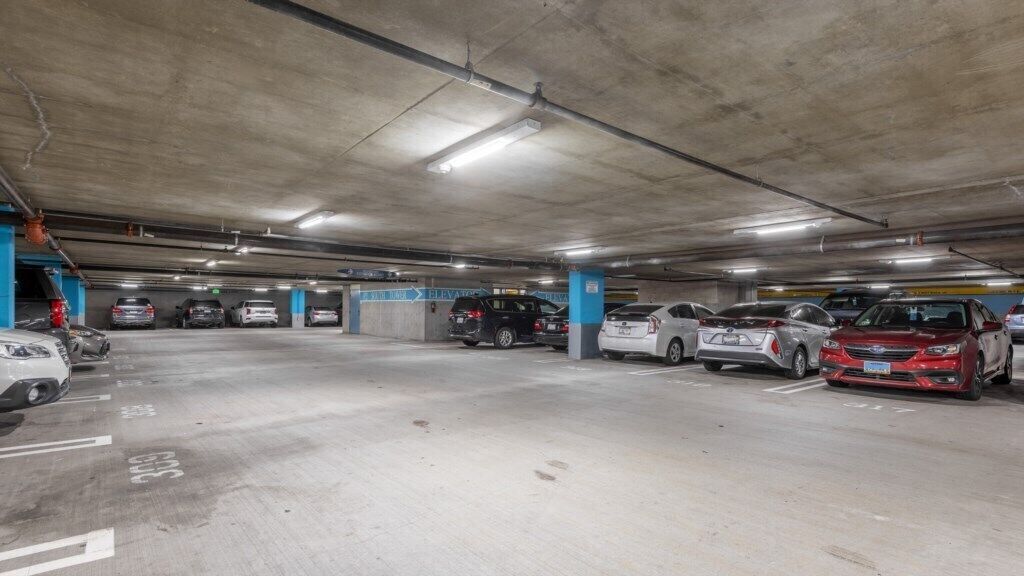 Eine mehrgeschossige Tiefgarage mit mehreren Autos in dafür vorgesehenen Stellplätzen.