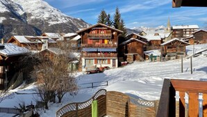 Un village de montagne enneigé, avec des bâtiments en bois et un télésiège.