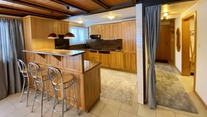 Une cuisine moderne avec des meubles en bois, un îlot central doté de tabourets et des luminaires suspendus.