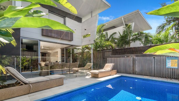 A modern outdoor pool area with lounge chairs and a glass-enclosed patio. - Kokos Beach House 4 (Byron Bay)