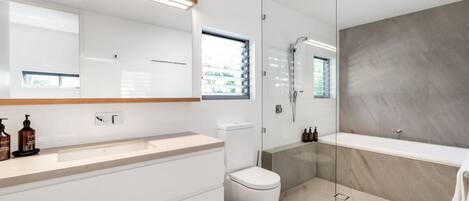 A modern bathroom with a glass-enclosed shower, a white toilet, and a bathtub.