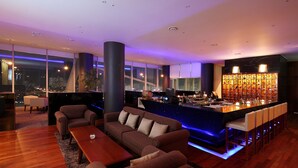 Een moderne bar met een toog, zitplaatsen en uitzicht over de stad.