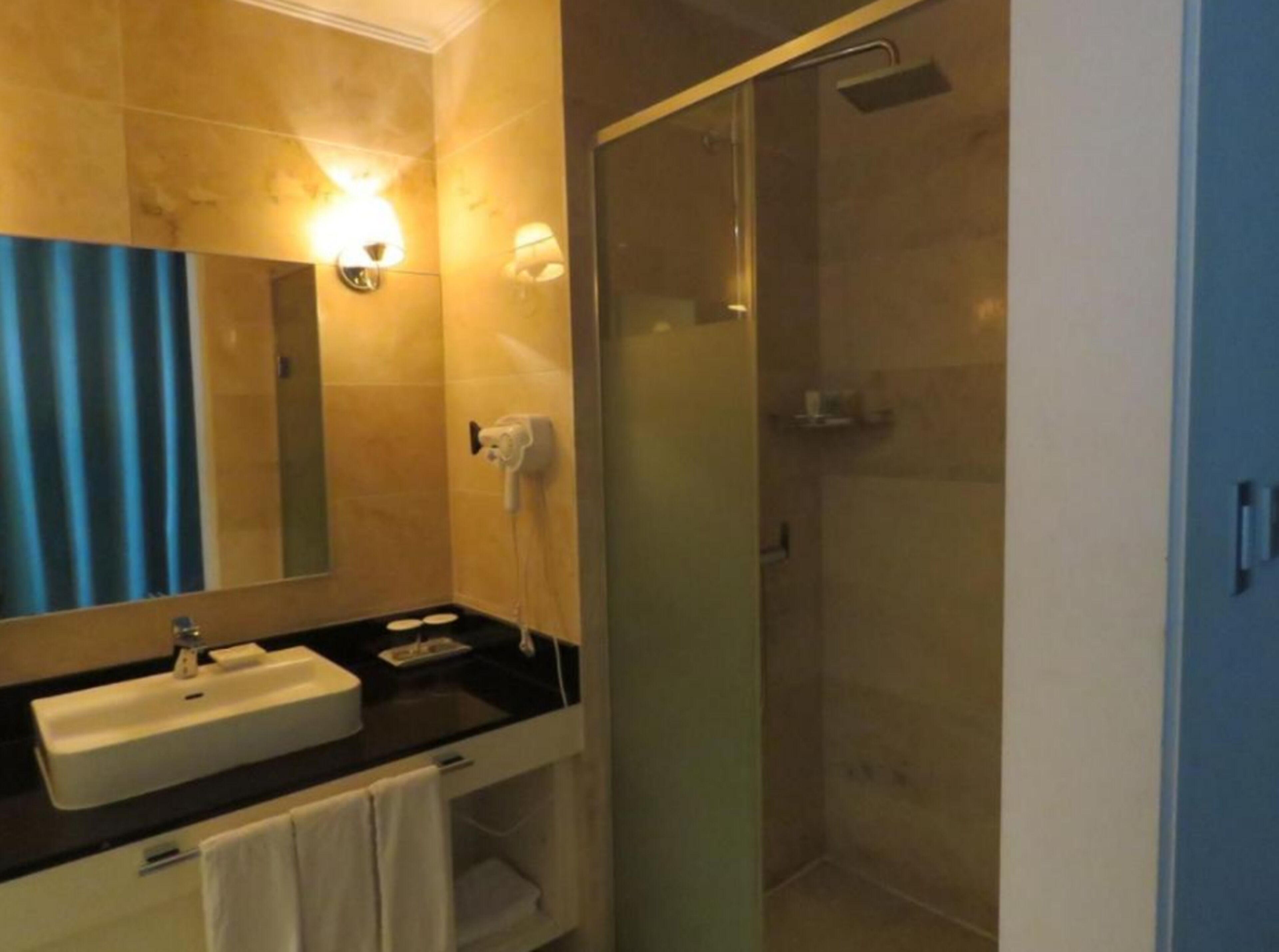 A bathroom with a large mirror, a sink, a towel rack, and a glass-enclosed shower.