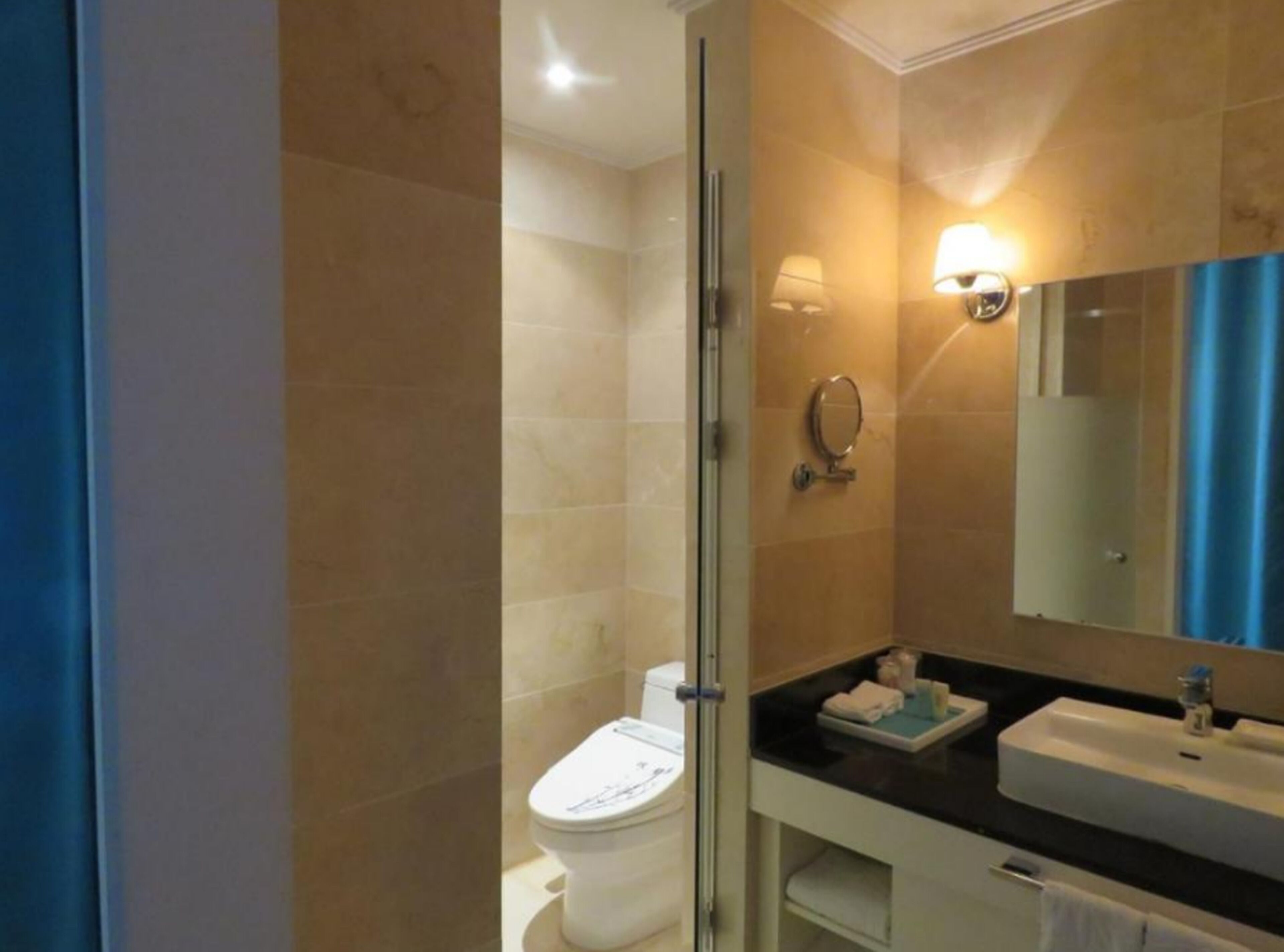 Un baño moderno con cabina de ducha de vidrio, inodoro, lavamanos y espejo.