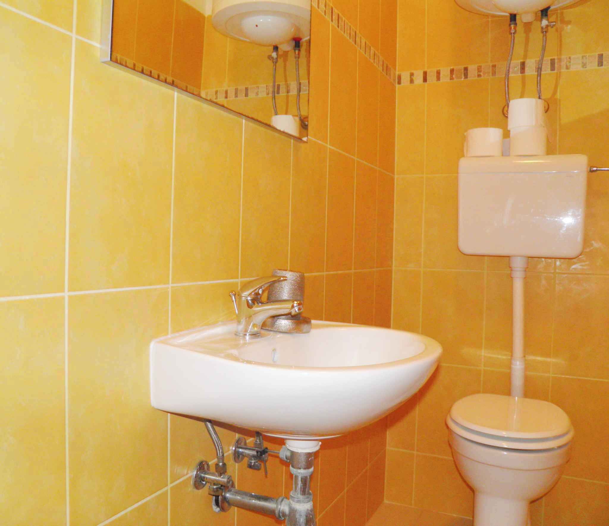 Ein Badezimmer mit weißem Waschbecken, Toilette und Spiegel.