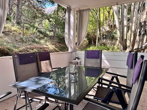 An outdoor patio with a glass table, chairs, and a view of a forested area. - Holiday apartment with air conditioning, internet and terrace (Baška)
