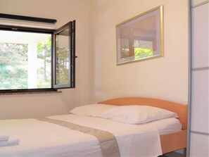 Ein Schlafzimmer mit Bett, Fenster und einem gerahmten Bild an der Wand.
