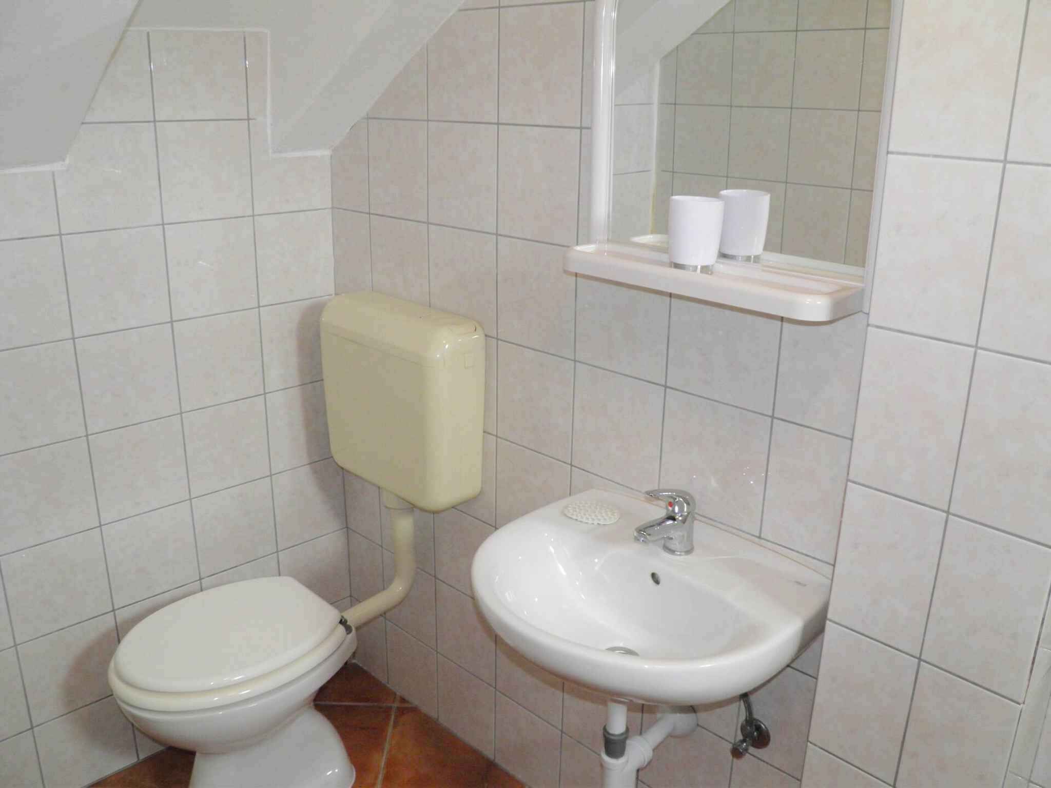 Une petite salle de bain comprenant des toilettes, un lavabo et un distributeur de savon.
