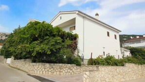 Un edificio blanco con un muro de piedra y un gran árbol al frente.