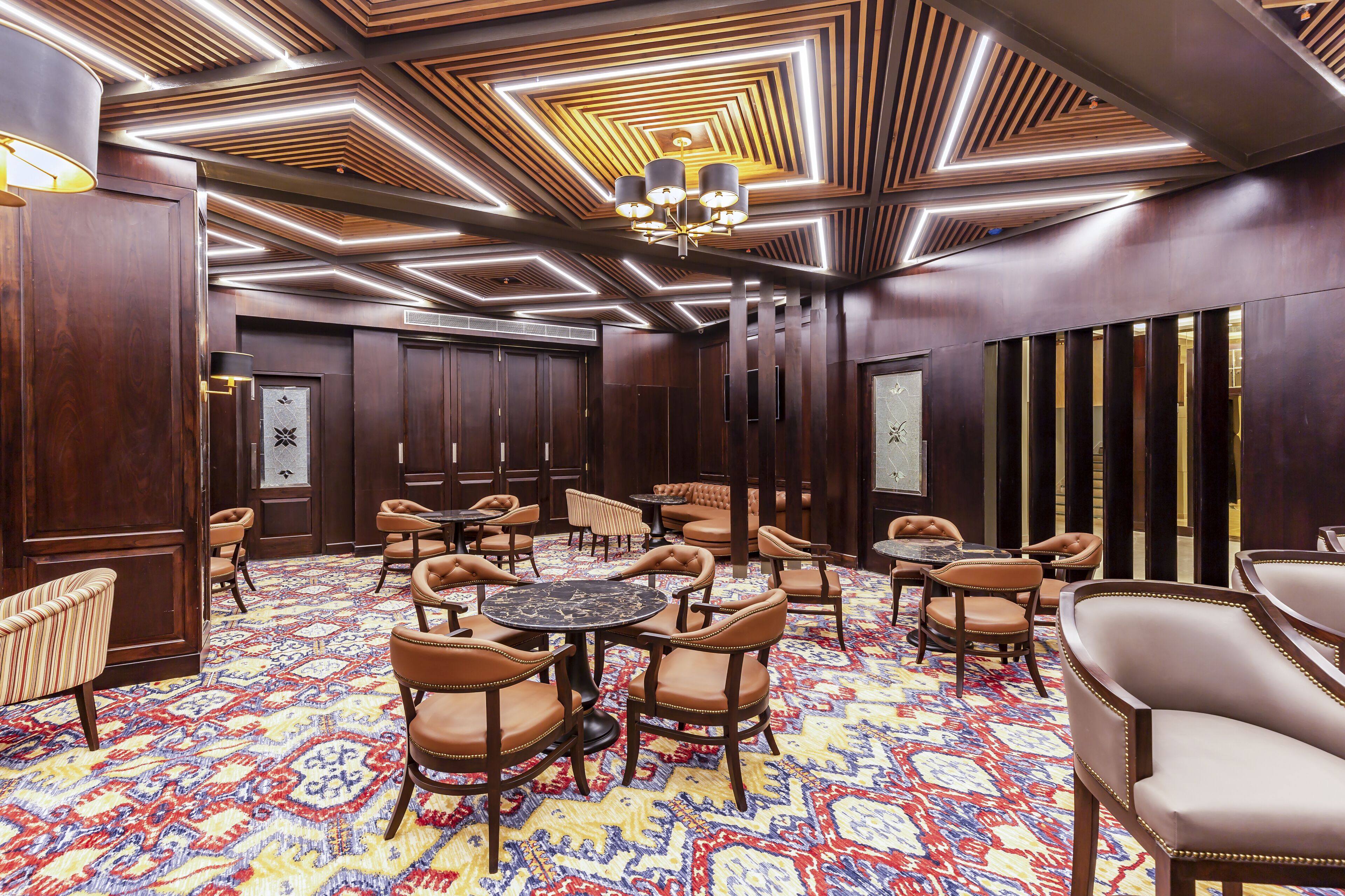 Eine Hotelhalle mit einem gemusterten Teppich, Holzwandverkleidung und einem Kronleuchter.