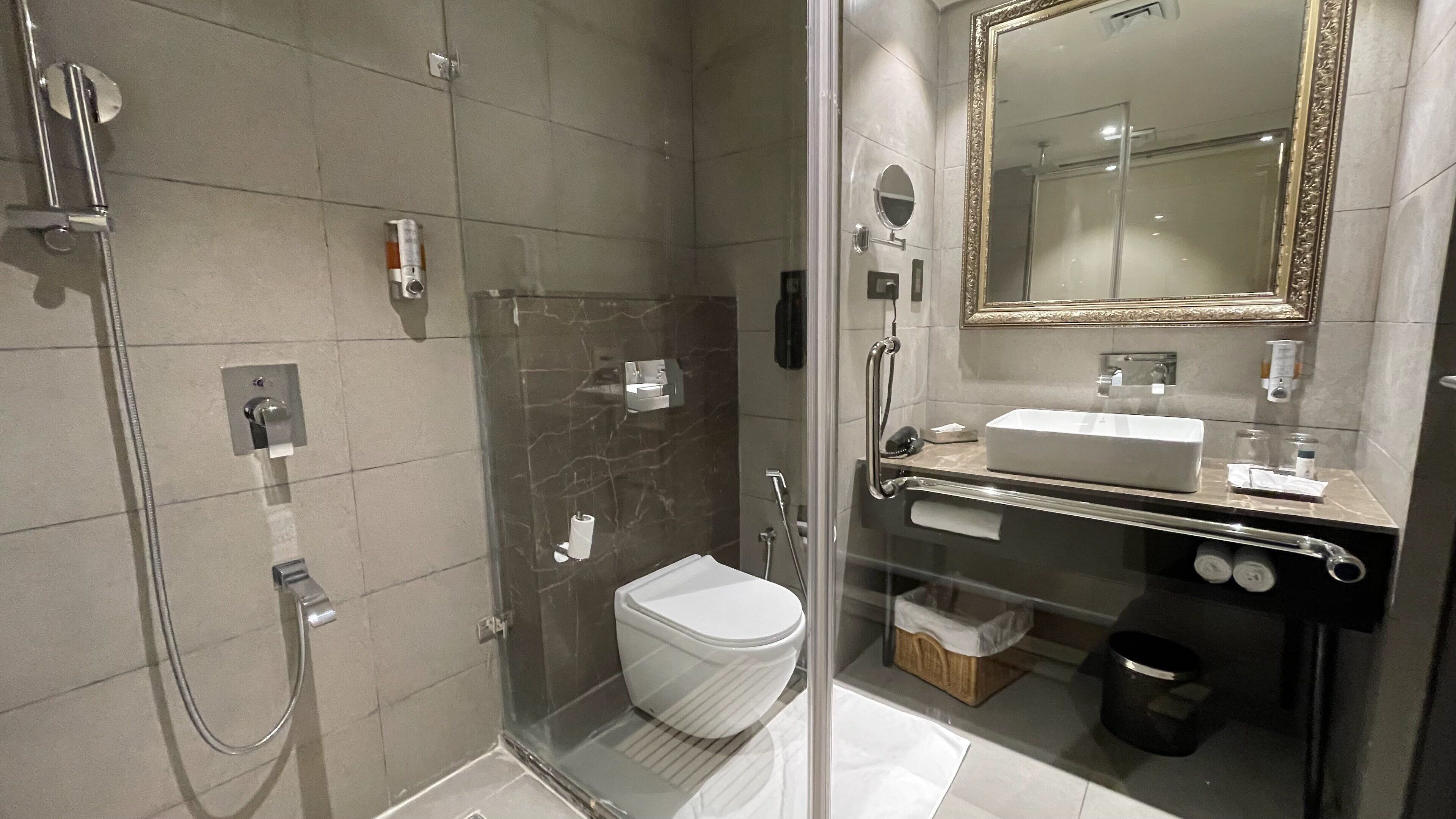 Un baño moderno con ducha de vidrio, inodoro blanco y tocador con espejo.