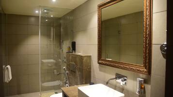 A modern bathroom with a glass shower enclosure, a marble vanity, and a large mirror with an ornate frame.