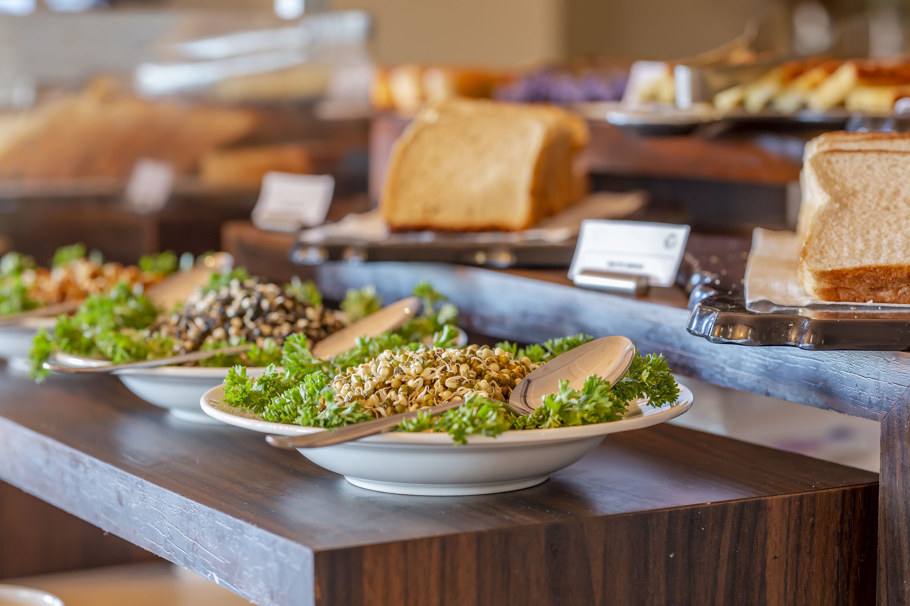 A buffet with various dishes, including salads, bread, and other food items.
