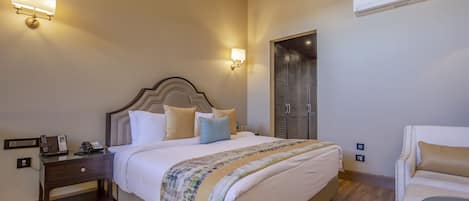 Una habitación de hotel ordenada con una cama grande, mesitas de noche, una silla y un armario.