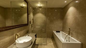 Een moderne badkamer met een grote spiegel, een vrijstaand bad en een douche met glazen wanden.