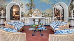 A room with wicker furniture, a glass table, and a mural on the wall. - Palazzo Villa dei Nobili (Sant'Agnello)