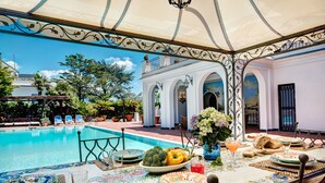 A dining area with a pool view, outdoor seating, and a decorative ceiling. - Palazzo Villa dei Nobili (Sant'Agnello)