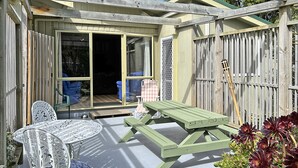 A patio area with a table and chairs, a wooden deck, and a wooden fence. - Te Rangimarie a fully fenced pet friendly home 20minutes walk from the beach. (Himatangi Beach)