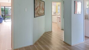 A hallway with light blue walls, wooden flooring, and a framed painting. - Te Rangimarie a fully fenced pet friendly home 20minutes walk from the beach. (Himatangi Beach)