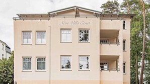 Een meerlaags gebouw genaamd "Neue Villa Ernst" met een symmetrische gevel, meerdere ramen en balkons.