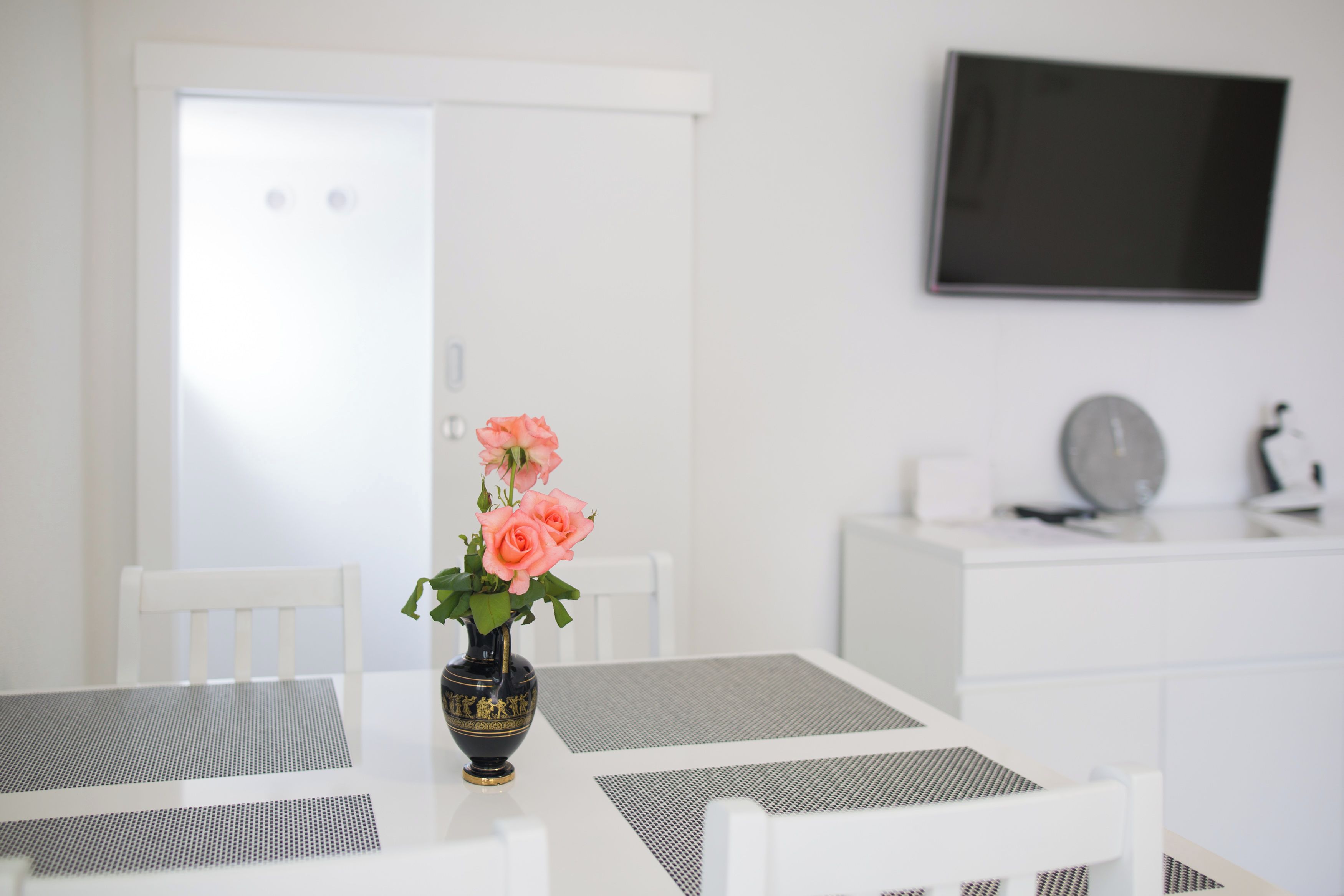 Un coin repas aux couleurs claires, avec une table, des chaises et un vase rempli de fleurs.