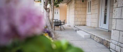Une cour avec une table et des chaises, une porte blanche et un mur en pierre.